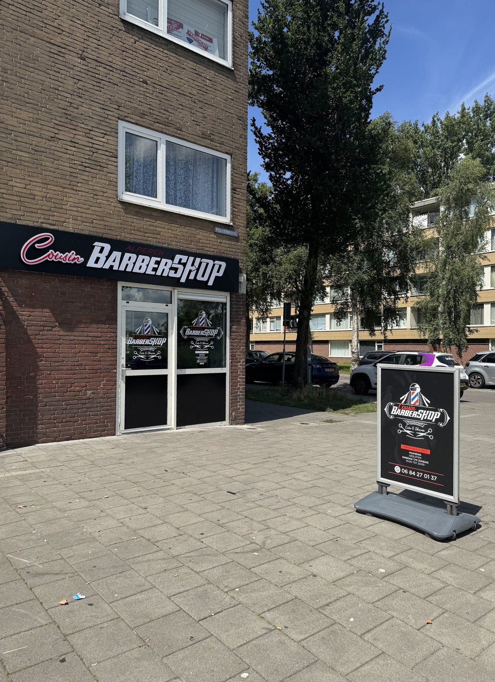 De gevel van Cousin barbershop aan de Linnaeusstraat met het zwarte bord en het stoepbord voor de deur