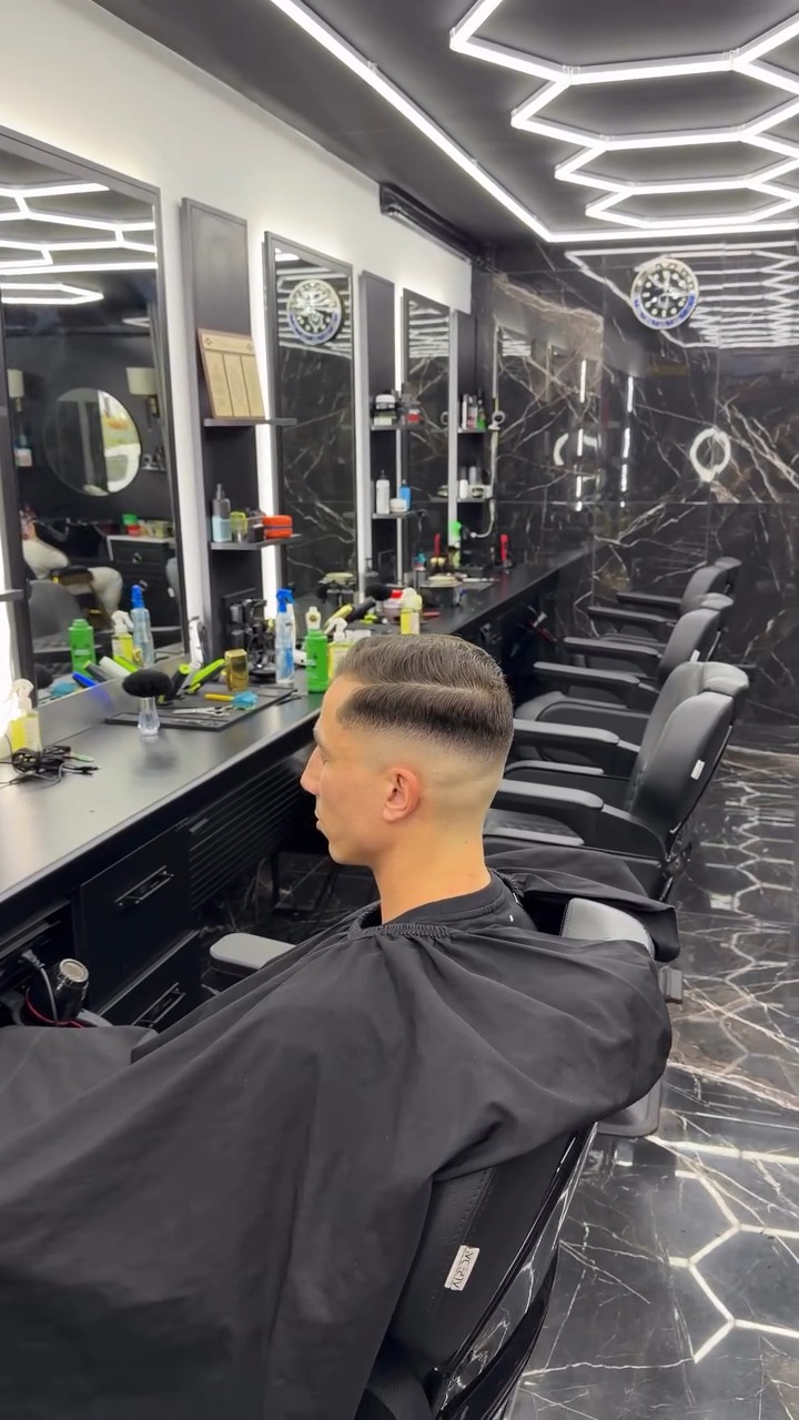 Verse fade van opzij gezien in de stoel, met de rij barberstoelen en spiegels erachter